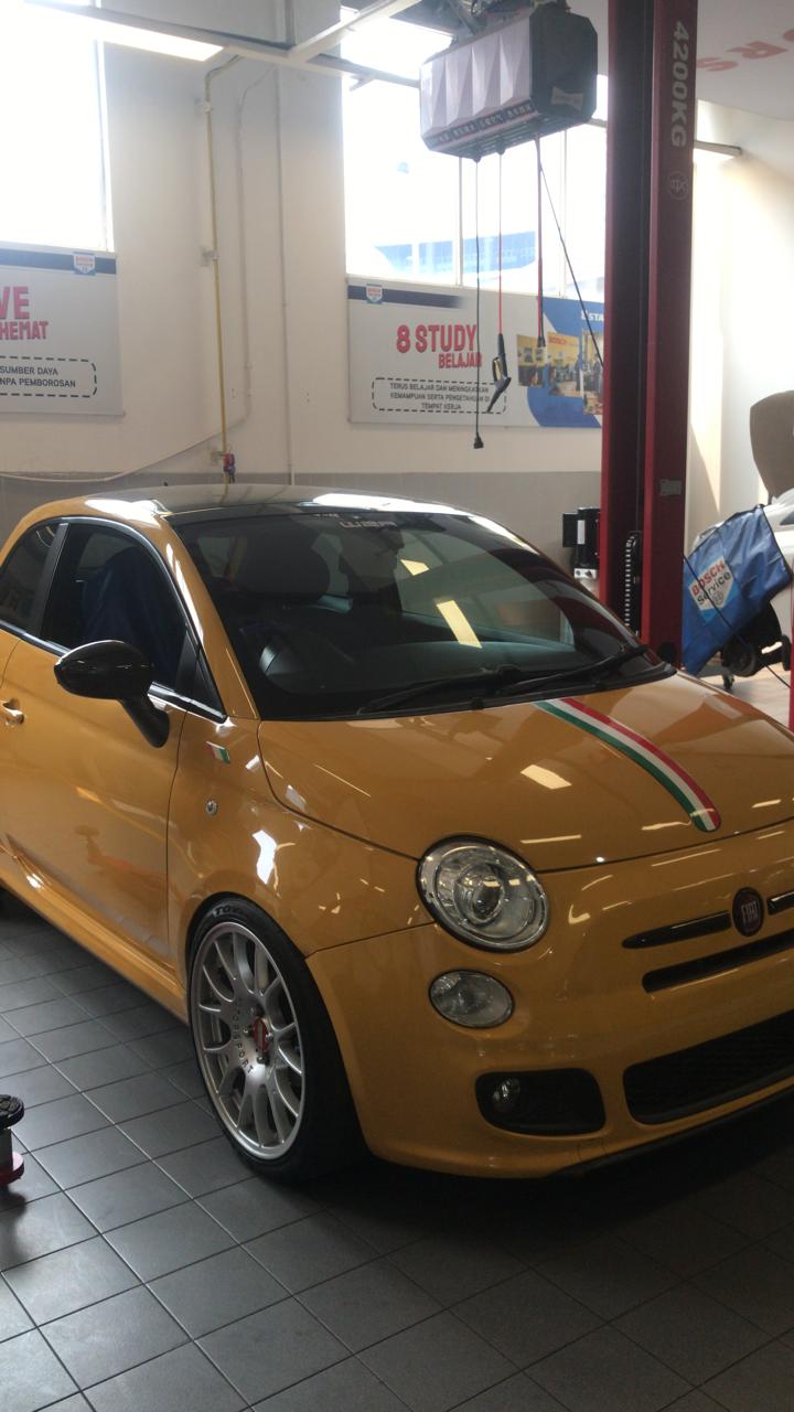 Mobil kuning di area workshop untuk inspeksi visual