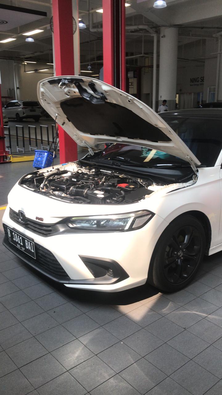 Dokumentasi inspeksi mobil dengan kap mesin terbuka di workshop